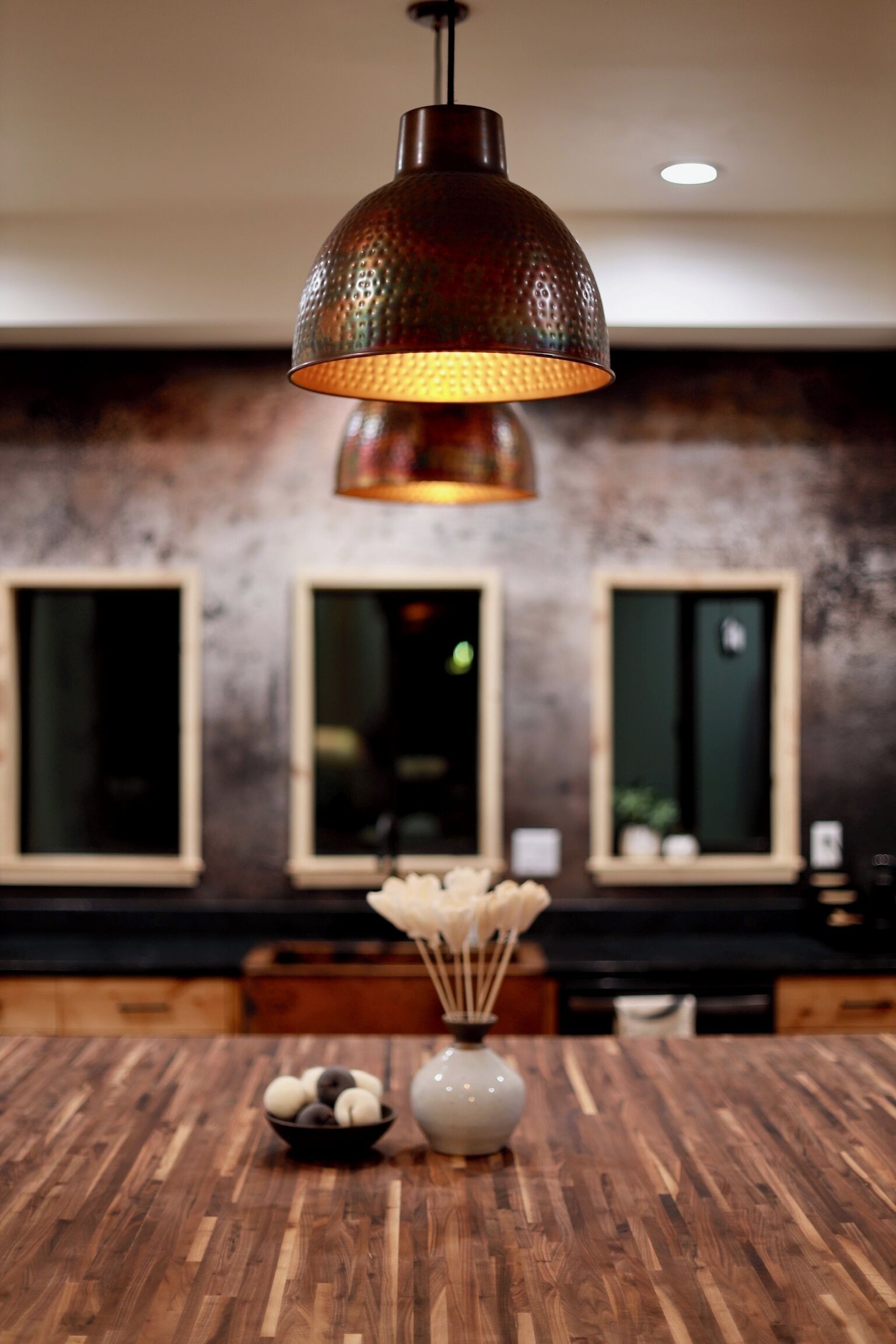 A dining area with a wooden table, a vase with decorative items, and a hanging light fixture.