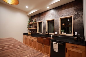 A modern kitchen with wooden cabinets, a black countertop, and a wooden dining table.