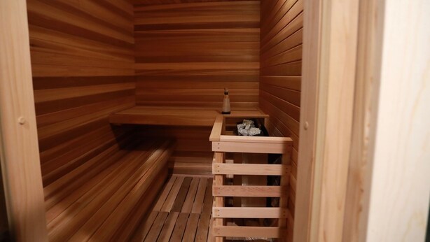 A wooden sauna with a bench, a small table, and a heating element. - The Black Copper Cabin. Escape to a luxury mountain retreat. (Alton)
