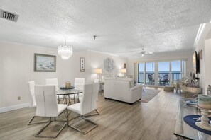 A spacious living area with a dining table, white sofas, and a balcony with a view. - Breathtaking Sunset Views | Beach Front Reflections In Indian Rocks Beach (Indian Rocks Beach)