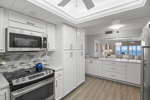 A modern kitchen with white cabinetry, a stainless steel range, a microwave, and a stove. - Breathtaking Sunset Views | Beach Front Reflections In Indian Rocks Beach (Indian Rocks Beach)