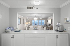 A kitchen with a large island, white cabinetry, and a view to a living area with a chandelier. - Breathtaking Sunset Views | Beach Front Reflections In Indian Rocks Beach (Indian Rocks Beach)