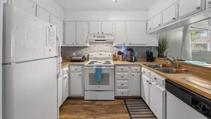 Una cocina moderna con armarios blancos, una estufa, un lavaplatos y un lavamanos.
