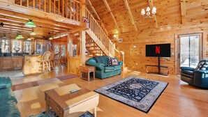 A spacious wooden cabin interior with a kitchen, dining area, living room, and a staircase leading to an upper level. - Shepardson Brookside: VAST+AT Hike | A/C | Brook (Stratton)