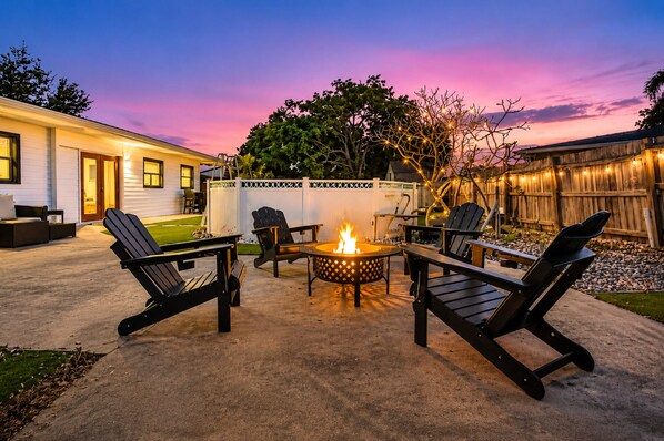 A backyard with a fire pit, outdoor seating, and a wooden fence. - Poolside Playhouse - Pool Home - 5 Min. To Beach (Seminole)