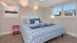 Una camera da letto con un letto, un comodino rosso, una ventola a soffitto e una finestra vista.
