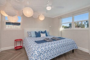 A bedroom with a bed, a red side table, a ceiling fan, and a window with a view. - Poolside Playhouse - Pool Home - 5 Min. To Beach (Seminole)