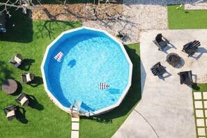 An octagonal swimming pool with a ladder, surrounded by lawn chairs and a concrete deck. - Poolside Playhouse - Pool Home - 5 Min. To Beach (Seminole)