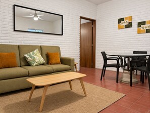 A living room with a sofa, a coffee table, a dining table with chairs, a mirror, and a door. - 5 de Diciembre 1BR 4 Blocks to Camarones Beach (Puerto Vallarta)