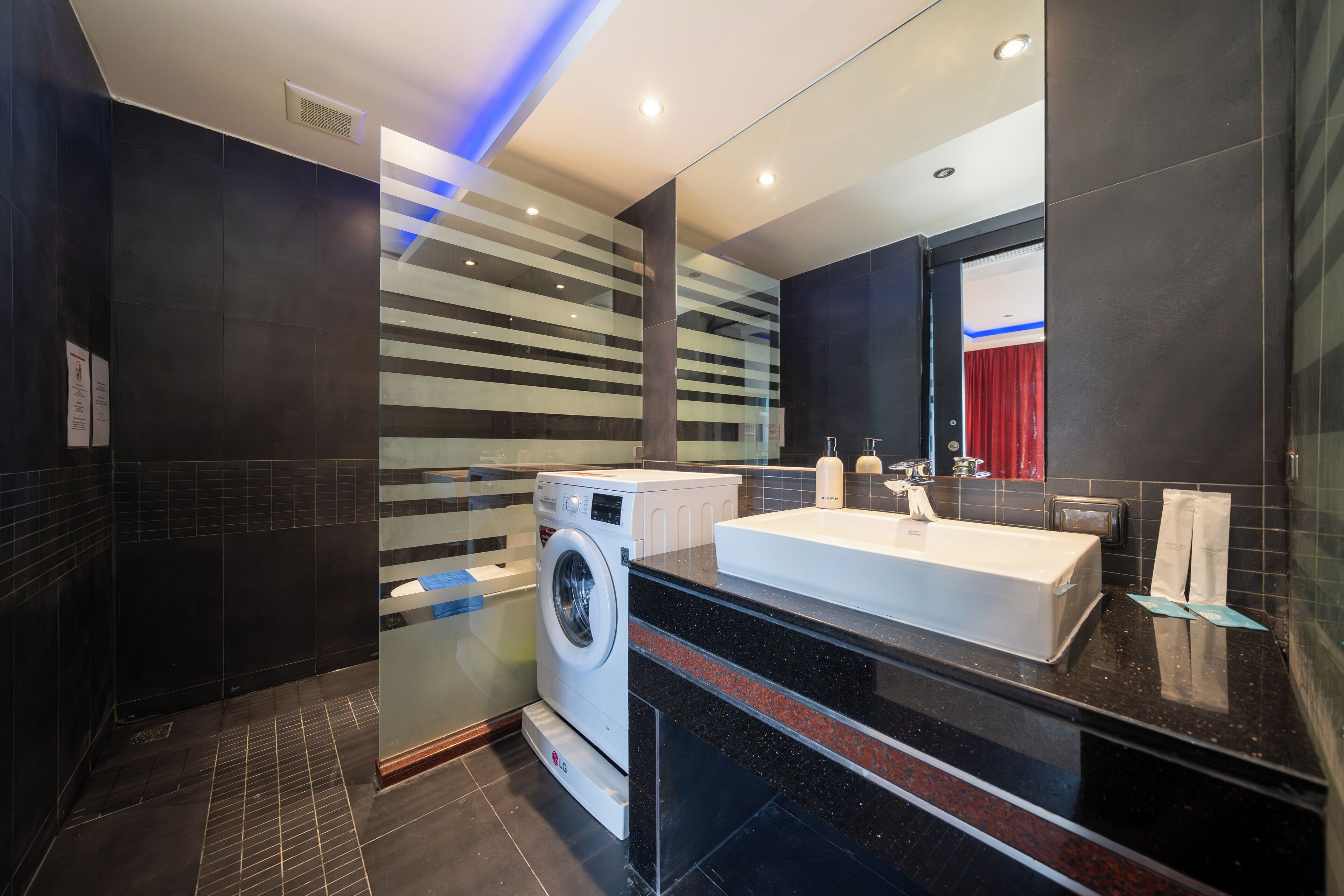 Un baño moderno con un espejo grande, una lavadora y un lavabo.