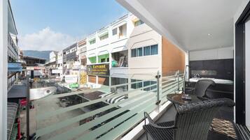 Ein Balkon mit Glasgeländer, der auf eine Straße mit Geschäften und einem Restaurant namens "Levant" blickt.