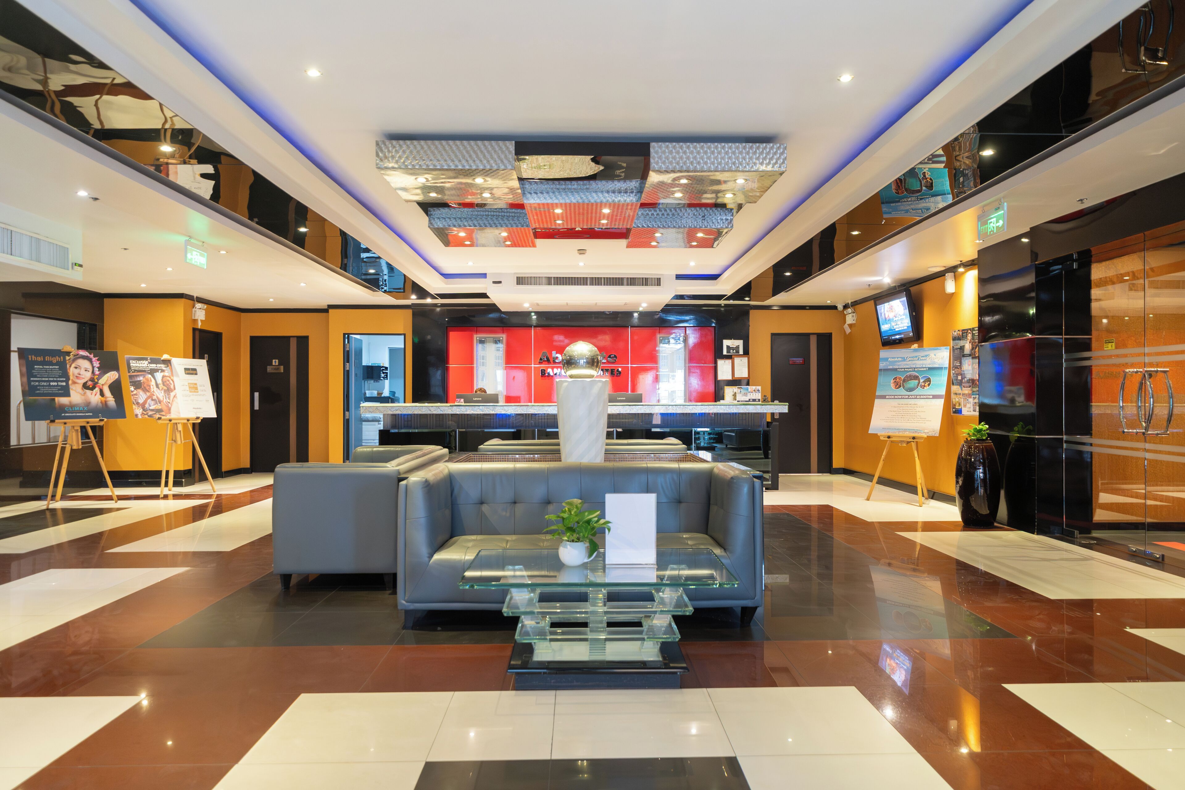 A modern lobby with a central seating area, a reception desk, and a large digital screen.