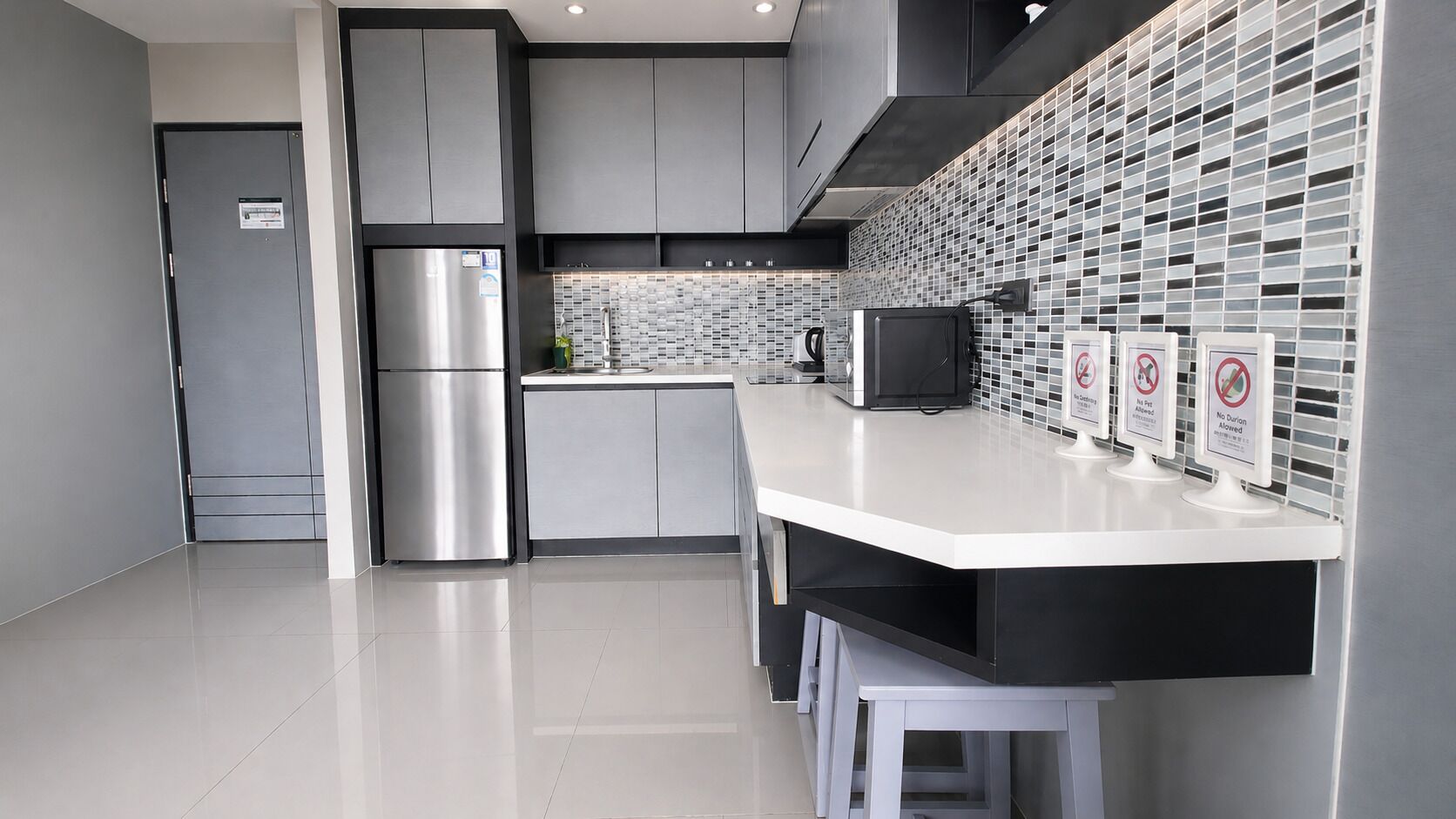 Een moderne keuken met roestvrijstalen apparatuur, een wit aanrecht en een betegelde spatwand.