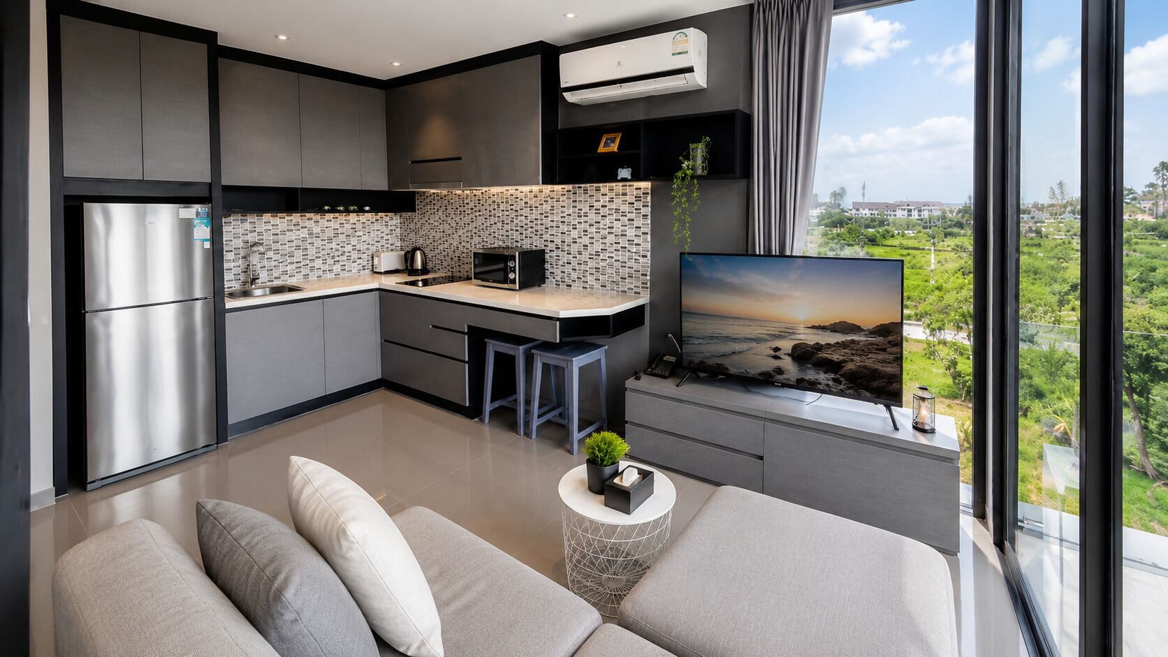 Eine moderne Küche mit Einbauofen, eine Essecke mit kleinem Tisch und Stühlen und ein großes Fernsehgerät auf einem Schrank mit schöner Aussicht.