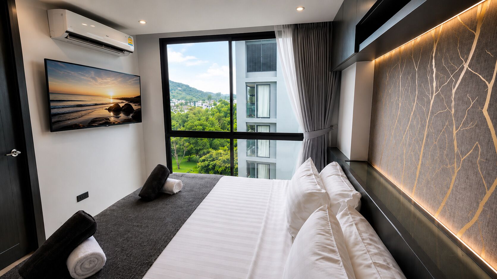 A modern hotel room with a large bed, a view of greenery, and a mounted TV.