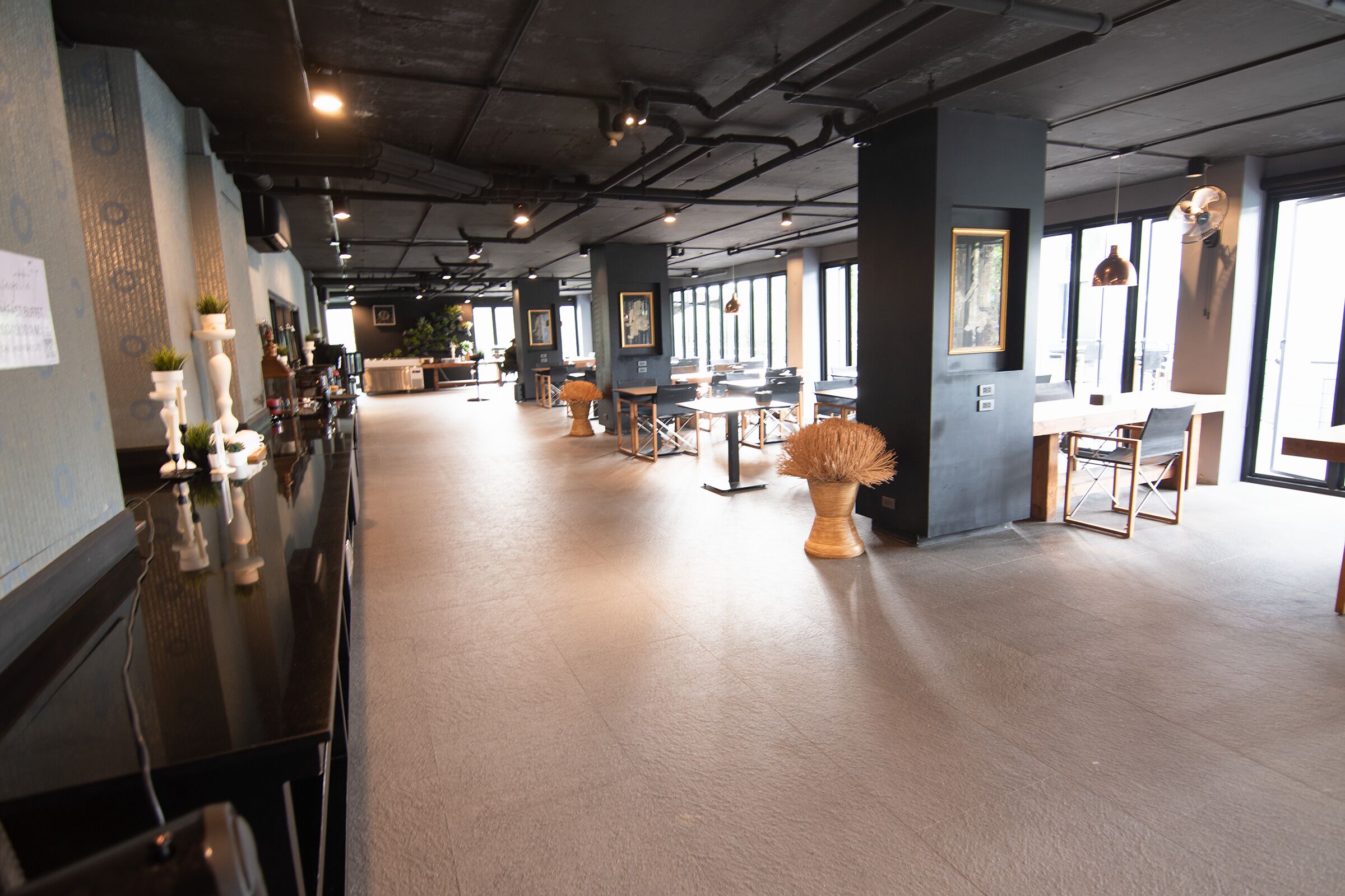 A spacious, modern interior with high ceilings, exposed ductwork, and large windows allowing natural light.