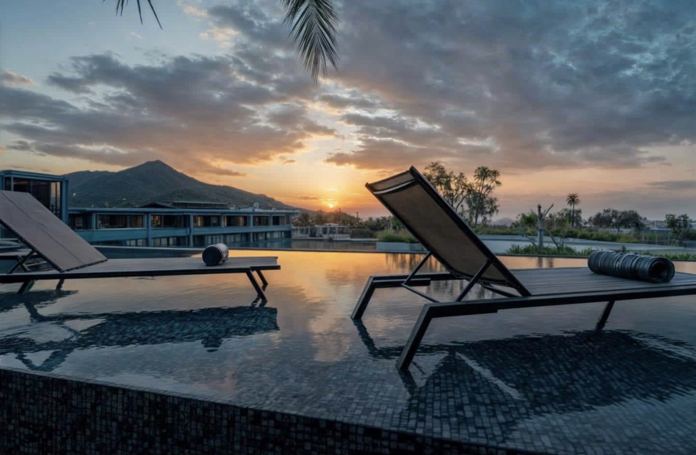 Ein Poolbereich mit Liegestühlen und Blick auf einen Berg bei Sonnenuntergang.