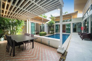 A modern outdoor patio with a pool, dining area, and lounge seating. - Mahogany 4Br Pool Villa In Bangtao (Choeng Thale)