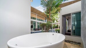 A modern bathroom with a large bathtub, a small pool, and a seating area with chairs and a table. - Mahogany 4Br Pool Villa In Bangtao (Choeng Thale)