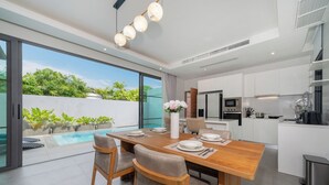 A modern kitchen with white cabinets, a stainless steel refrigerator, and a microwave. - Nicky Elegant 3Br Pool Villa Bangtao (Choeng Thale)