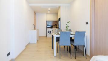 Eine kompakte Küche mit modernen Geräten, ein Essbereich mit Tisch und Stühlen sowie ein Holzboden.
