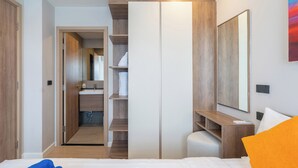 A modern hotel room with a bed, a wardrobe, a desk, and a bathroom visible through an open door. - Space Cherngtalay In Elegant Bangtao (Choeng Thale)