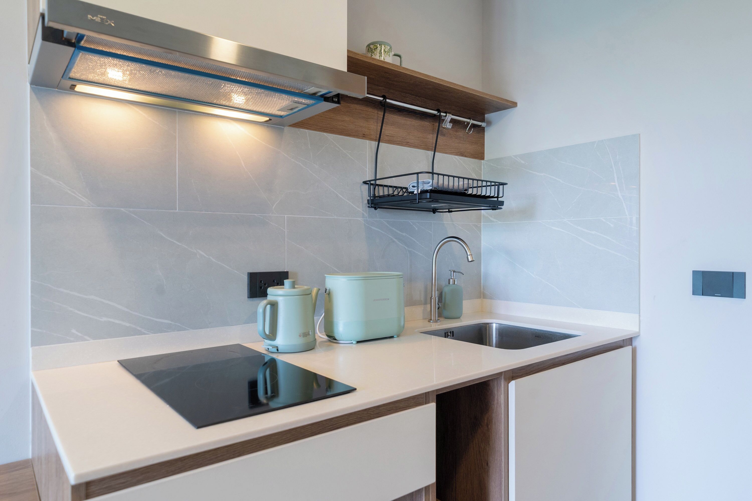 Una cocina moderna con encimera blanca, estufa integrada, fregadero y lámpara colgante.