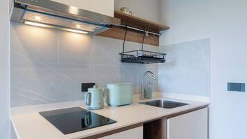 Una cocina moderna con encimera blanca, estufa integrada, fregadero y lámpara colgante.