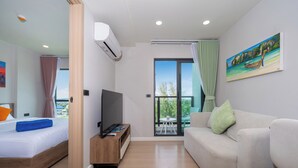A modern hotel room with a bed, a TV, a sofa, and a balcony with a view. - Space Cherngtalay In Elegant Bangtao (Choeng Thale)