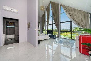 Quarto de hotel moderno com uma janela grande, uma cama, uma TV e um armário vermelho.