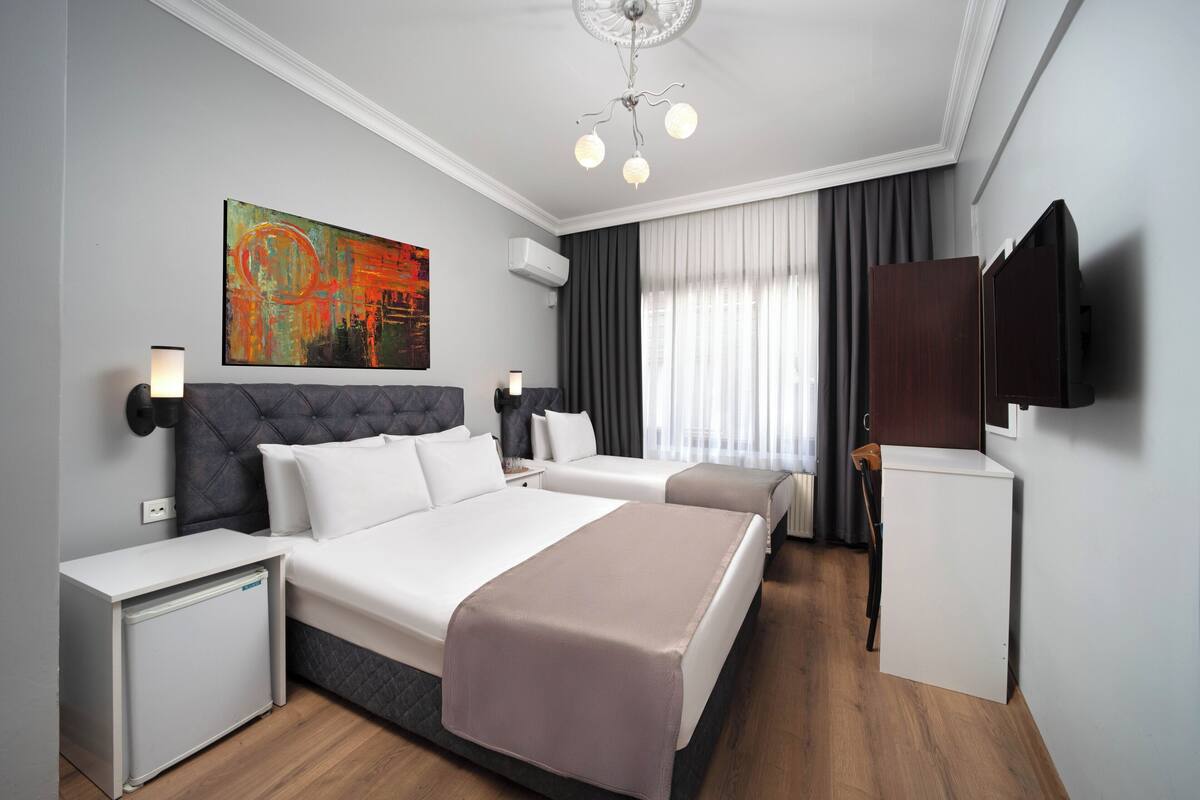 Ein Hotelzimmer mit einem großen Bett, Nachttischen, einem Flachbildfernseher und einem Bild an der Wand.