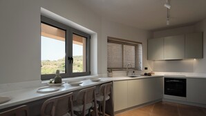 Cuina moderna amb un gran finestral, armaris integrats i zona de menjador amb caires.