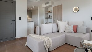 Un saló modern amb un sofà seccional gris, un armari de fusta i una cuina al fons.
