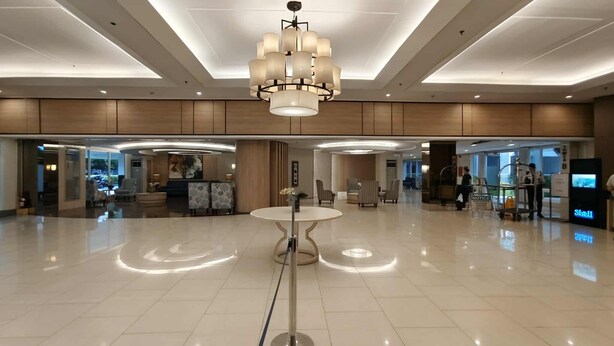 A spacious lobby with a modern chandelier, a reception desk, and a Shell gas station sign. - The Royal Bloom Room-1409TowerA (Pasay)