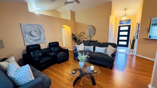Sala de estar com dois sofás pretos, uma mesa de centro de vidro e um quadro abstrato grande na parede.