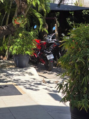A motorcycle parked in a shaded area with potted plants and a covered structure in the background. - Hotel in Tuxtla with comfortable rooms and a family-friendly, pet-friendly. (Tuxtla Gutiérrez)
