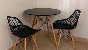 Una mesa pequeña y redonda con dos sillas negras de patas de madera.
