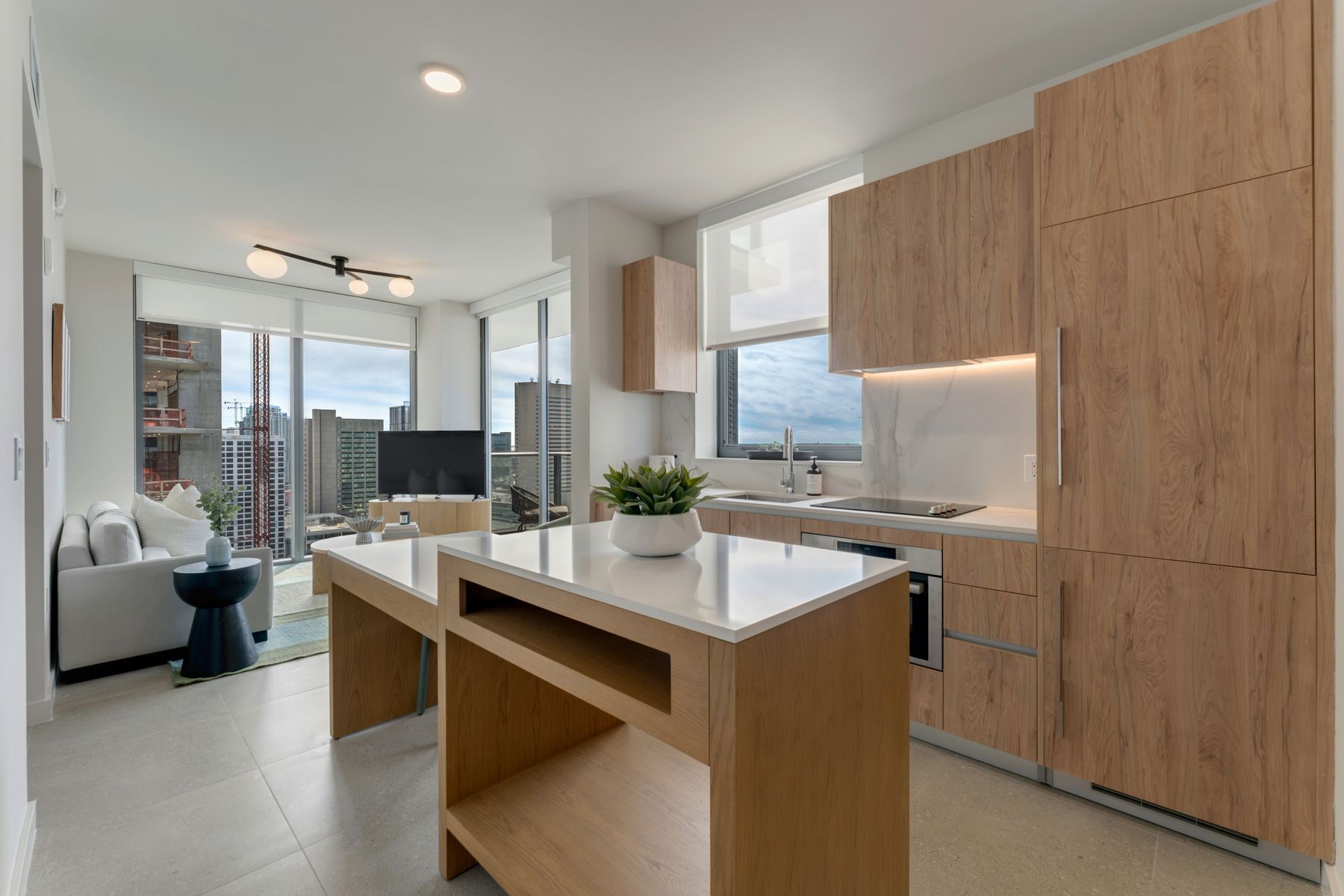 A modern kitchen with wooden cabinets, a large island, and a city view.