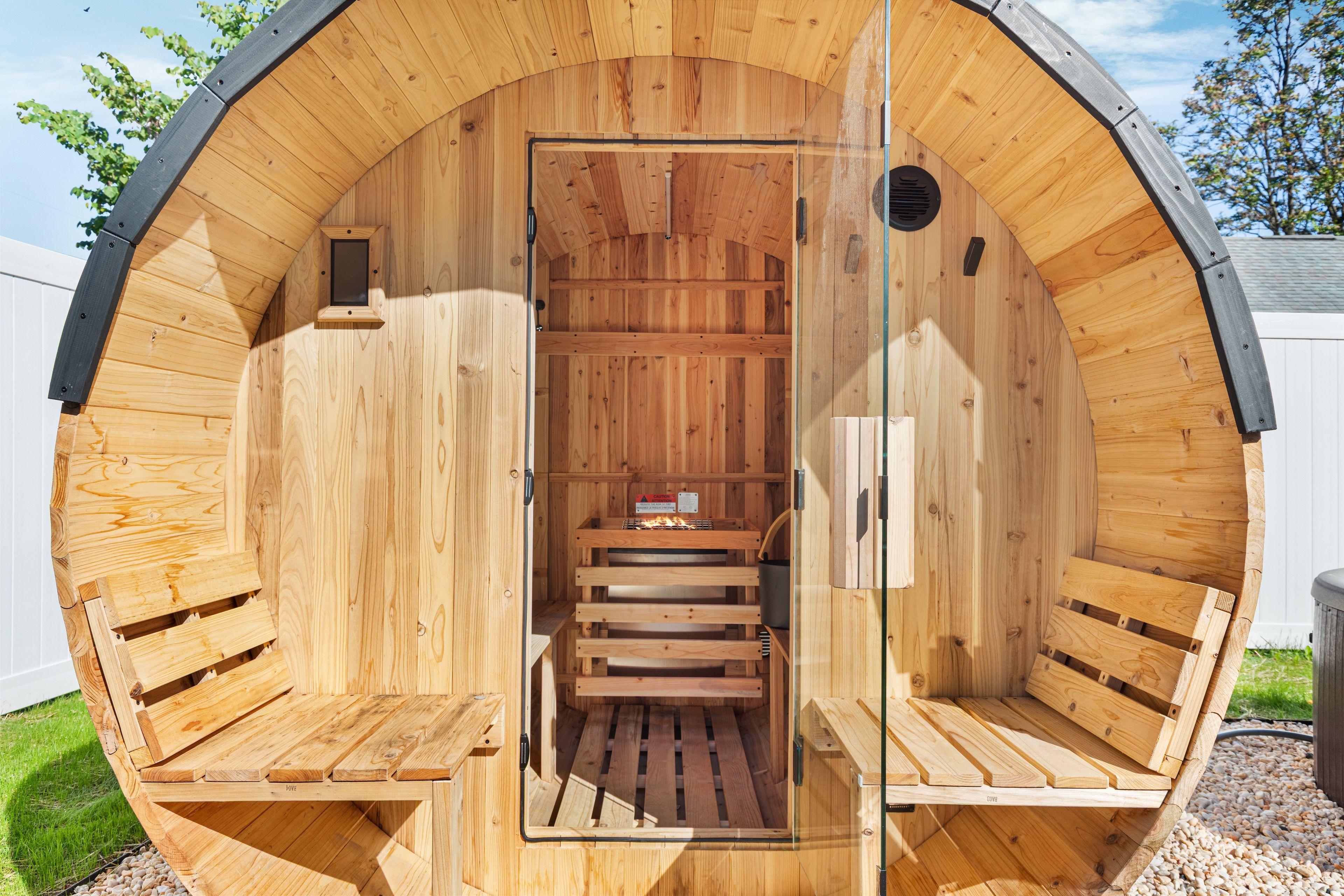 Una sauna de madera con techo curvo, una puerta central y bancos a ambos lados.