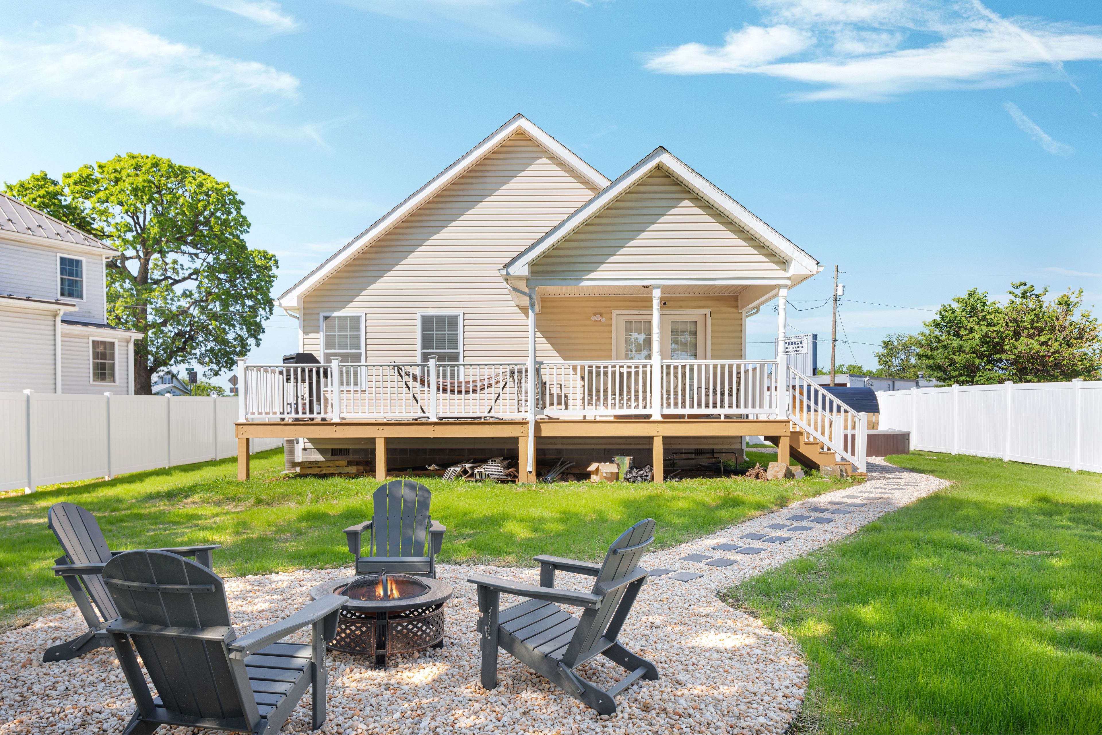 A two-story house with a deck and a fire pit in the backyard.
