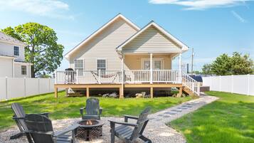 A two-story house with a deck and a fire pit in the backyard.
