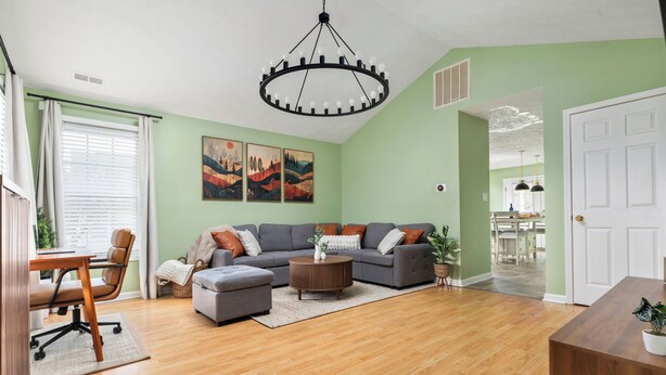 A living room with a sectional sofa, a coffee table, and a dining area with a table and chairs. - Heart of Luray: Sauna, Hot Tub & Fire Pit (Luray)