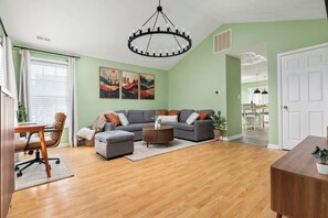 A living room with a sectional sofa, a coffee table, and a dining area with a table and chairs. - Heart of Luray: Sauna, Hot Tub & Fire Pit (Luray)