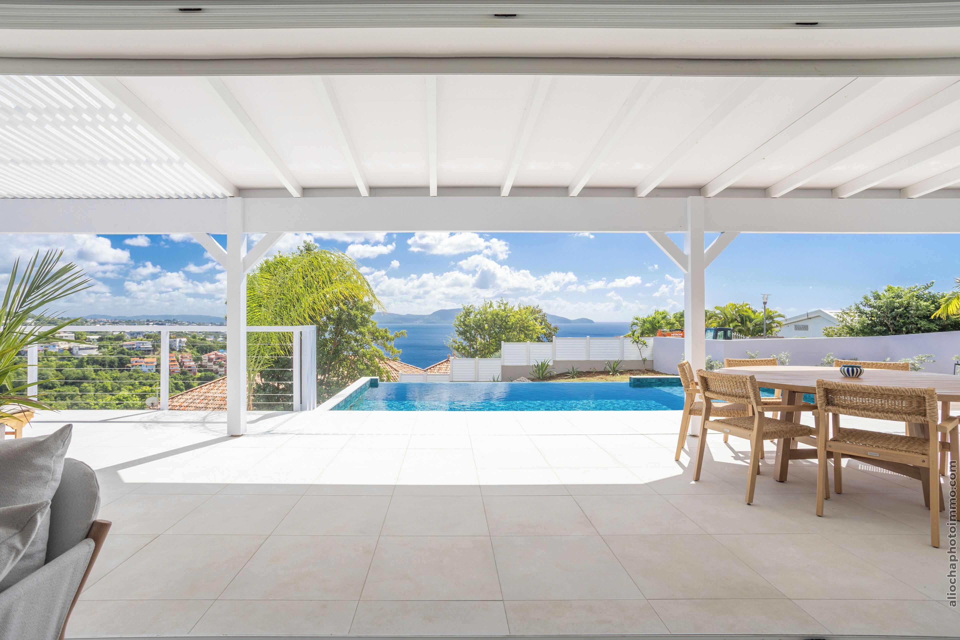A covered outdoor area with a pool, seating, and a view of the sea.