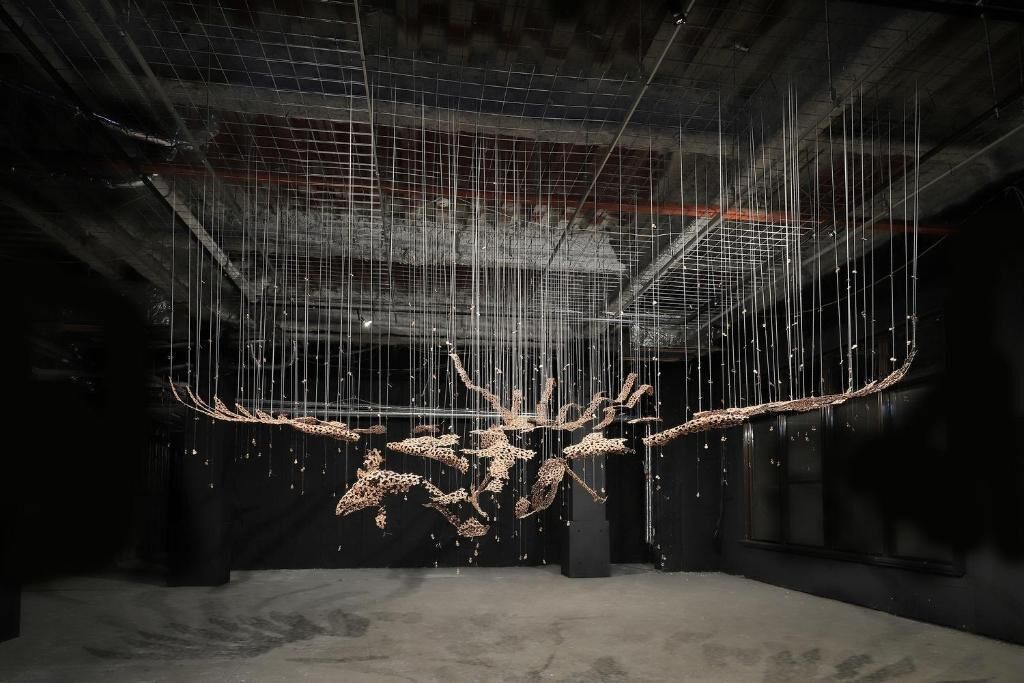 Una instalación artística con estructuras colgantes en un espacio industrial.