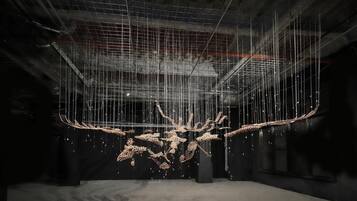 Una instalación artística con estructuras colgantes en un espacio industrial.