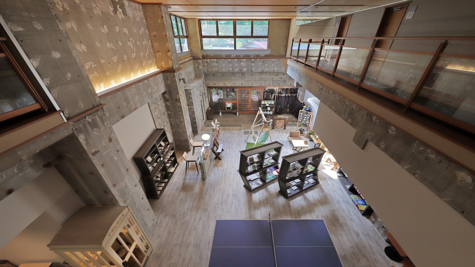 A multi-level interior with exposed concrete walls, a central open space with seating, and a visible staircase.