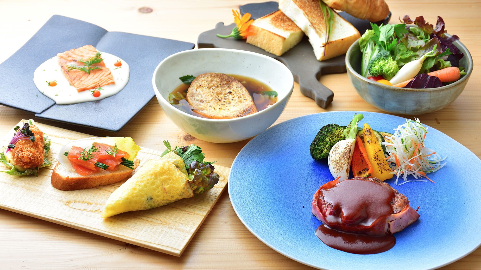 Une variété de plats, notamment du saumon, du pain et des légumes, présentés sur une table en bois.