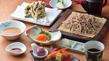 Une variété de plats japonais, notamment des sushis, des sashimis et des nouilles, servis dans des assiettes et des bols traditionnels en céramique.