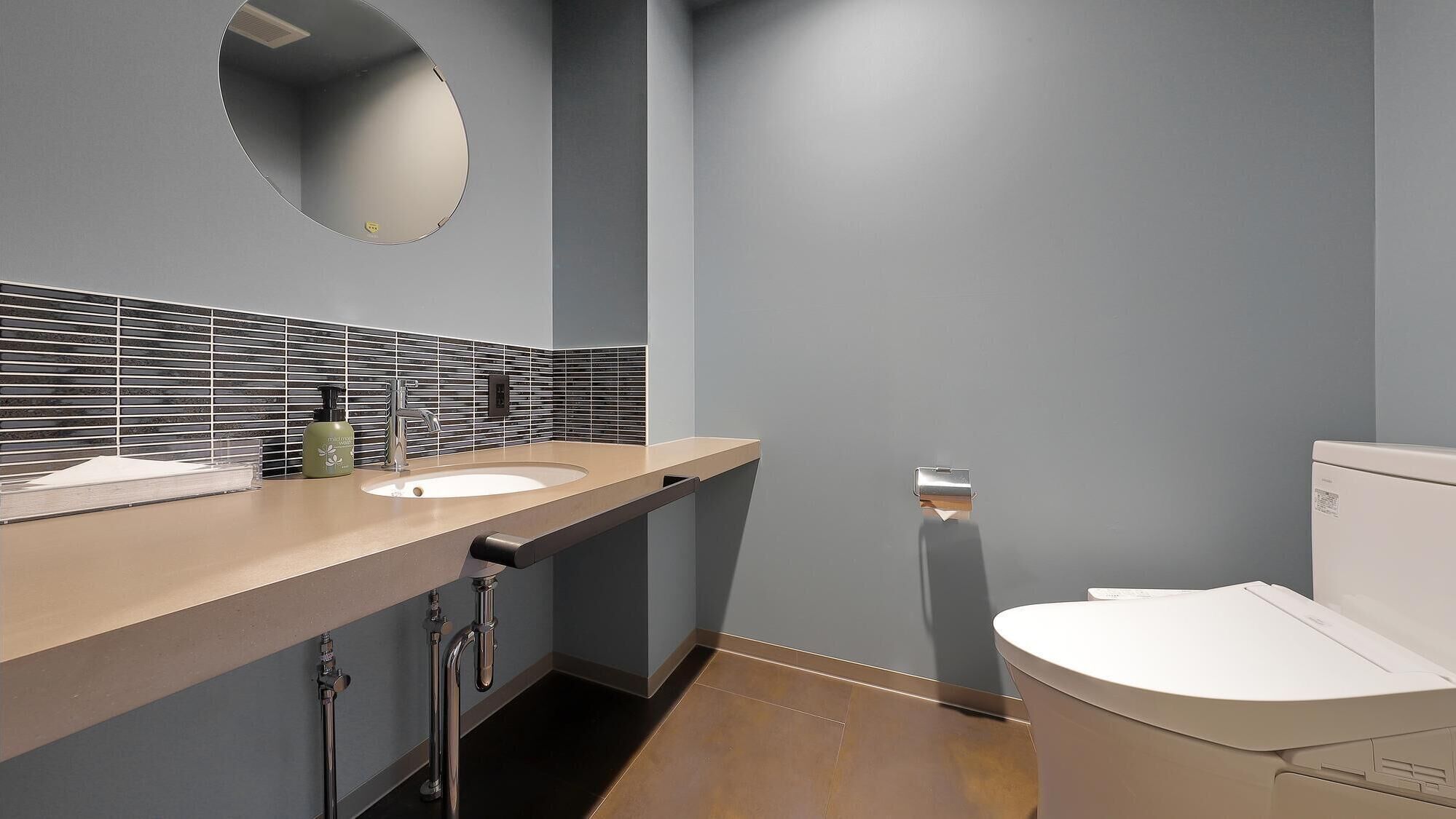Un baño moderno con dos lavamanos, un inodoro y un espejo.